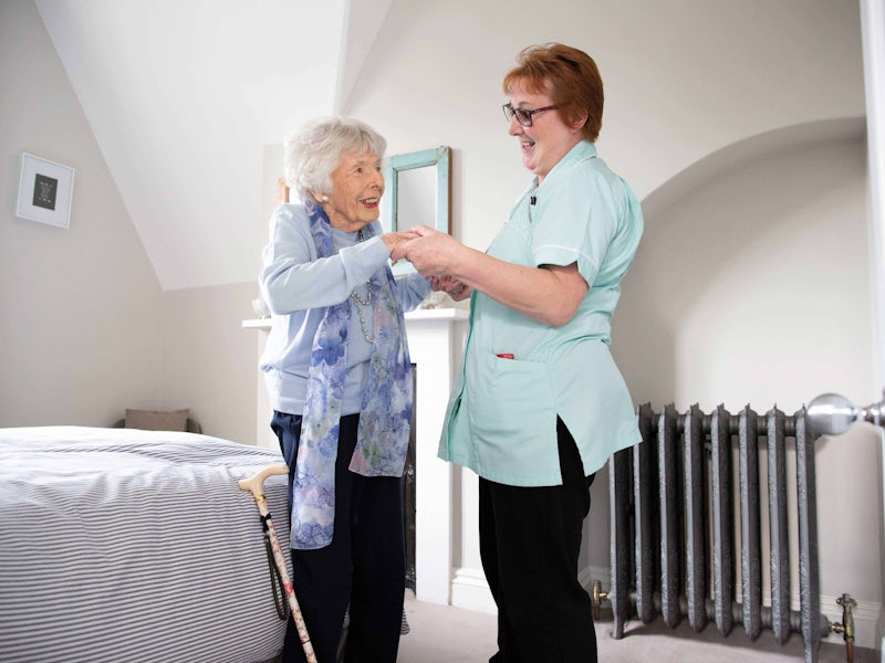 Nurse or carer helping an elderly woman stand up.