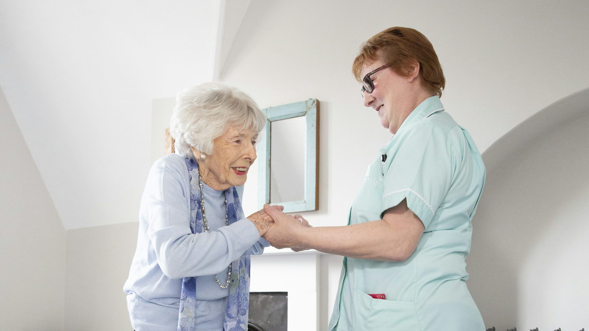 Nurse or carer helping an elderly woman stand up.