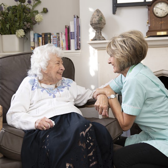 Elderly lady sat in a chair talking to her carer