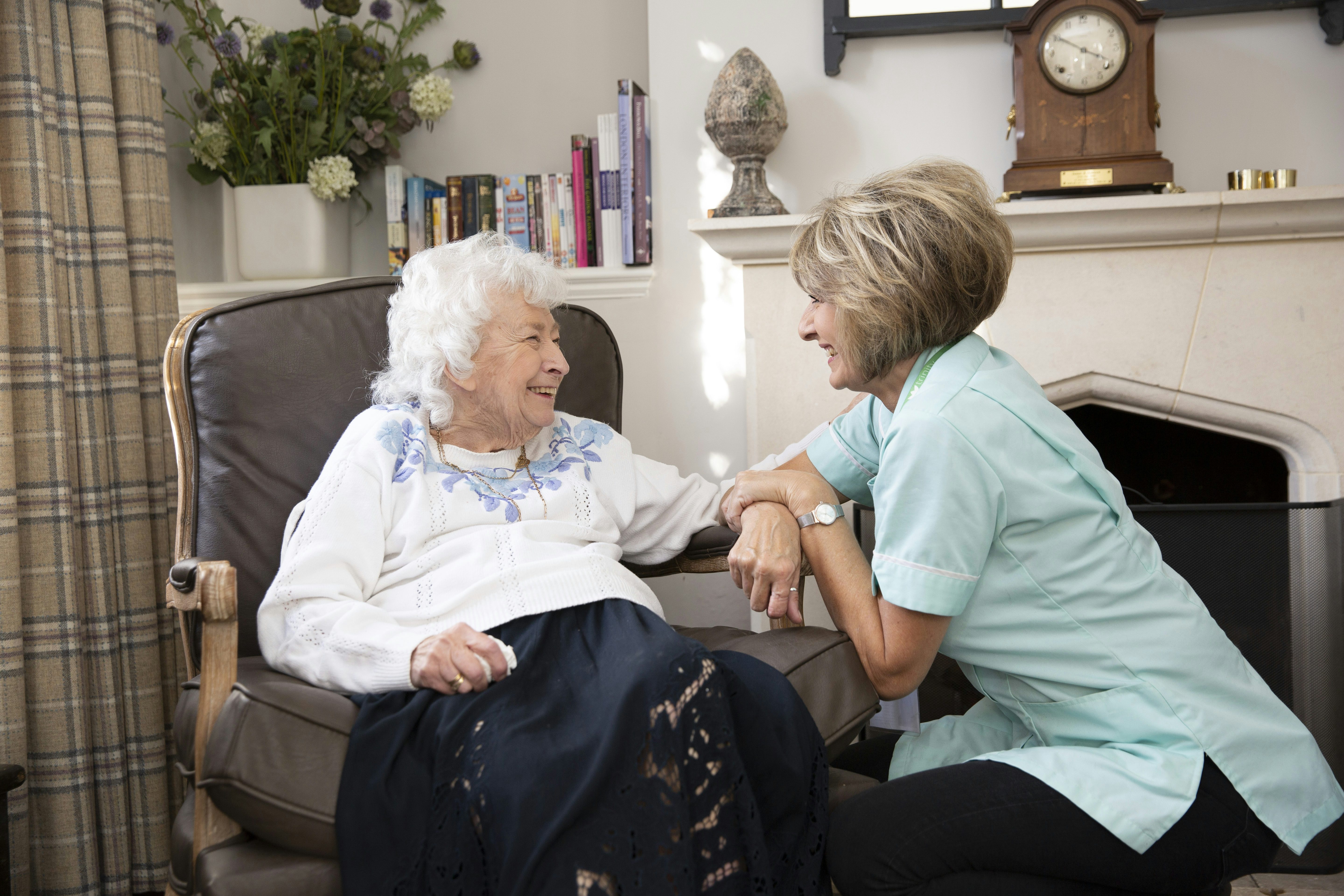 Elderly lady sat in a chair talking to her carer