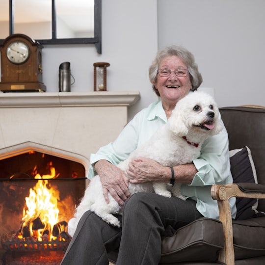 Elderly Lady sat in a chair with her per dog on her lap
