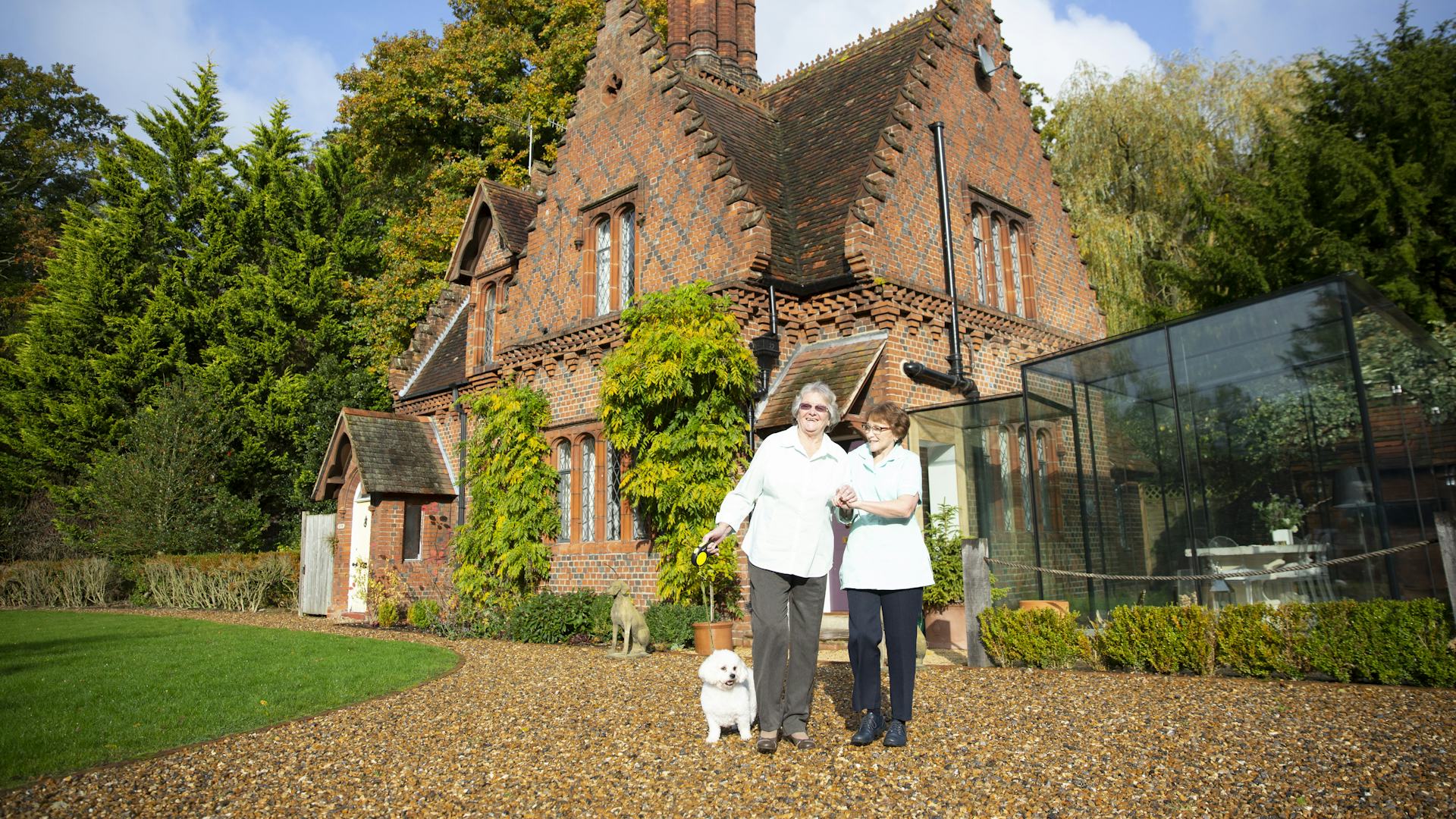 Carer and elderly lady walking her pet dog outside