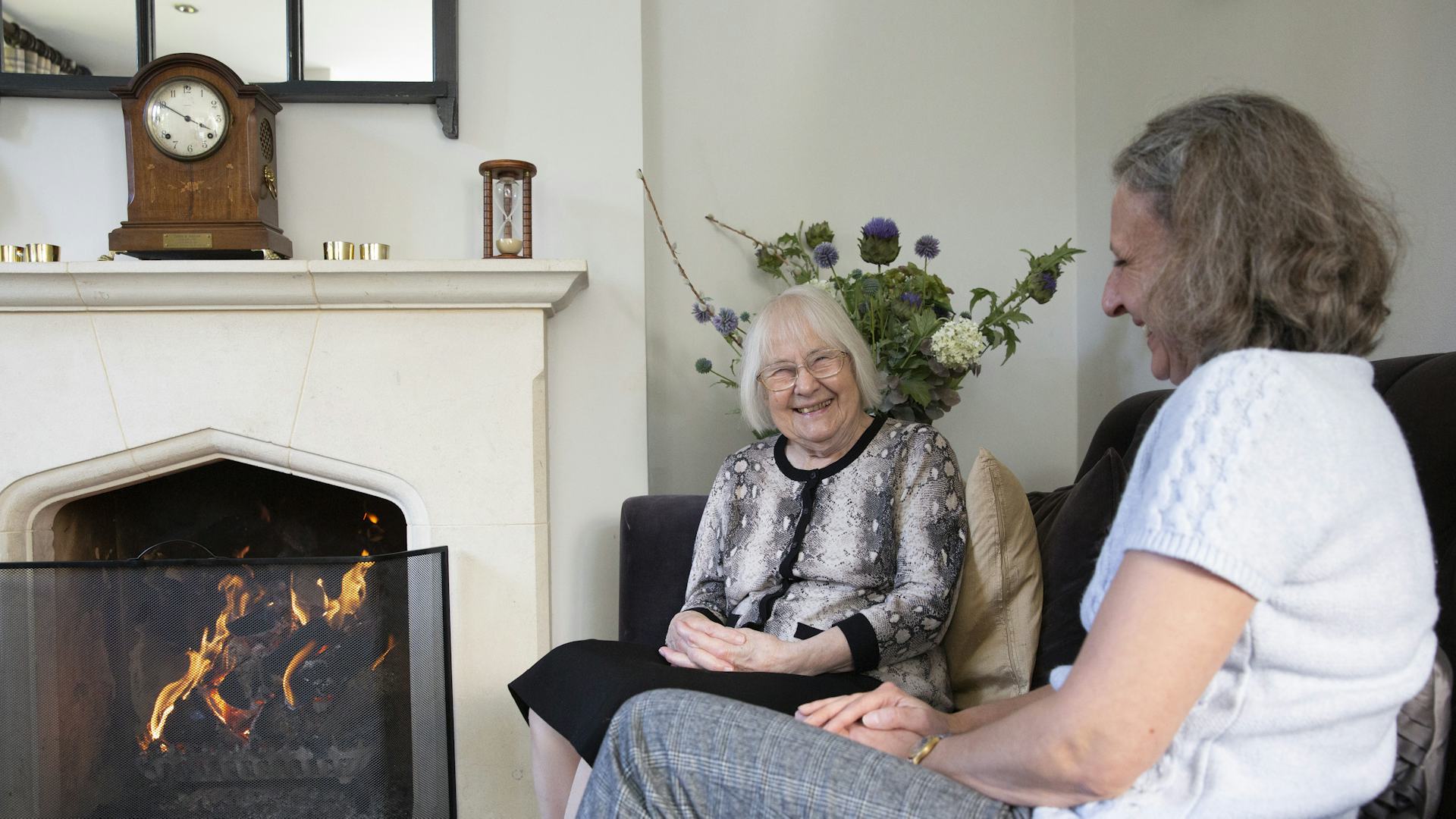 Two elderly ladies sat on a sofa laughing