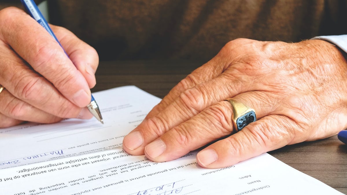 Elderly person signing a document