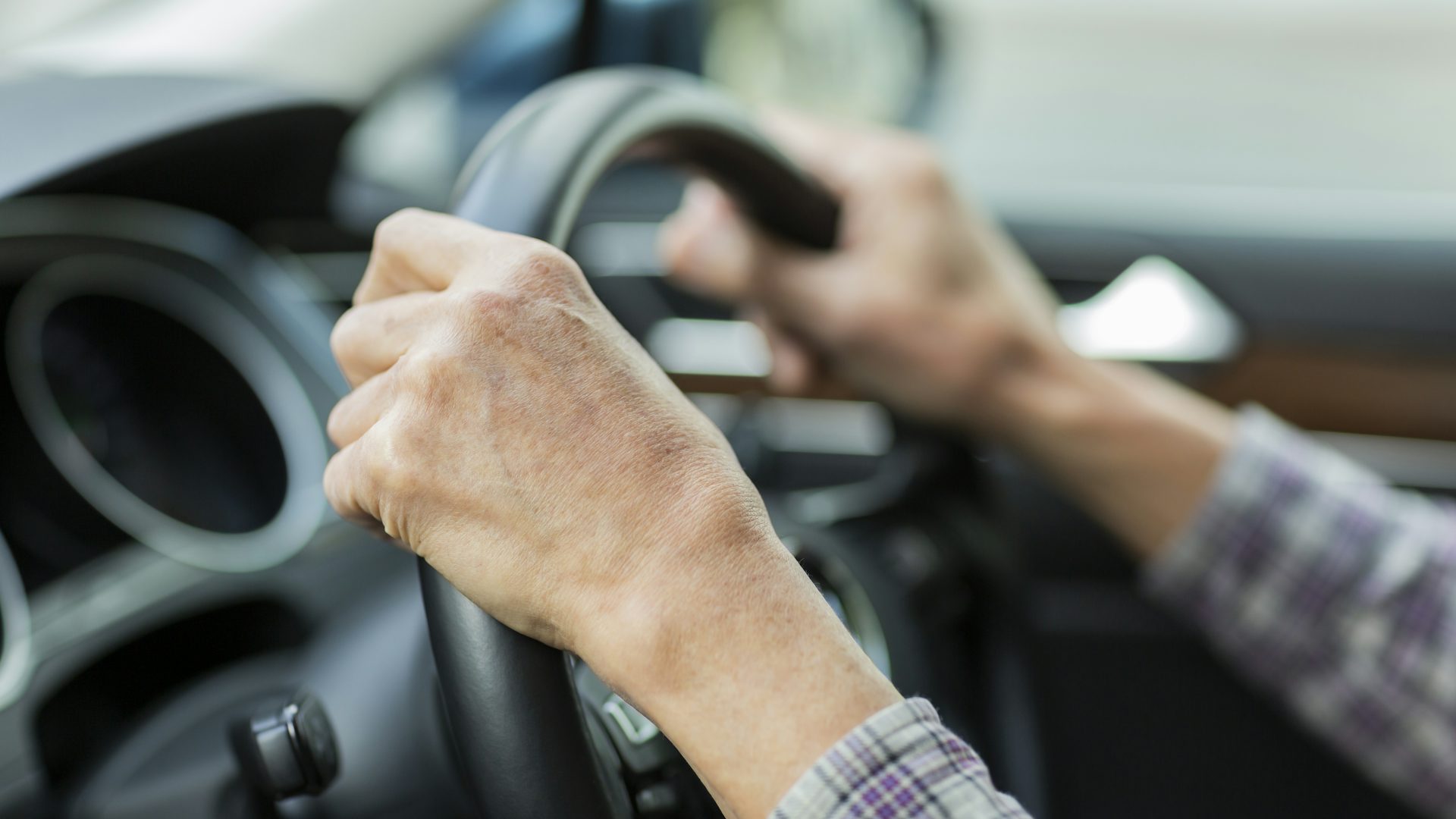 Elderly hands on a steering wheel